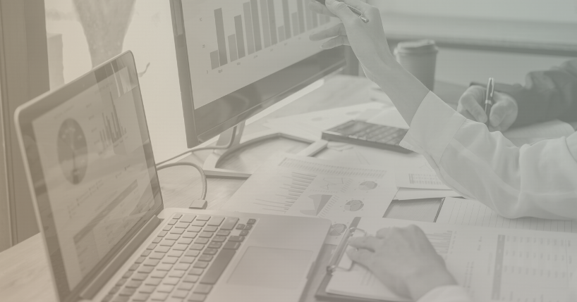 two people working on laptops with papers in front of them showing graphs and charts.