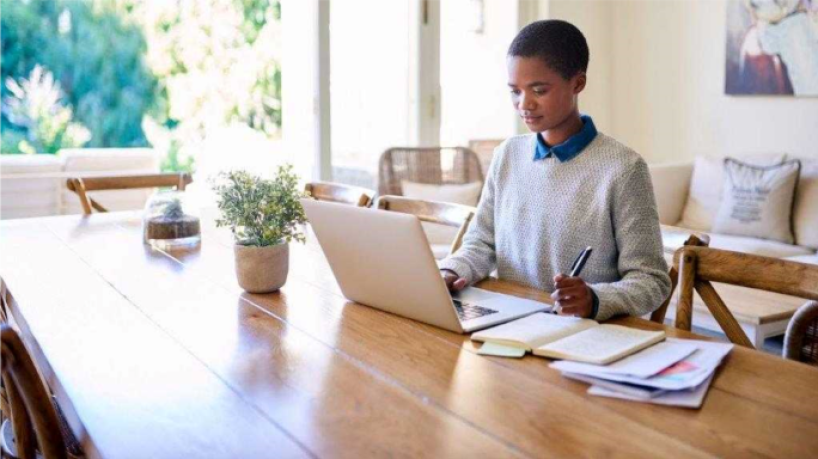 Woman sitting at table working on laptop computer.