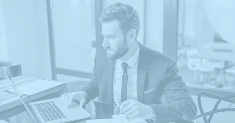 Man in business suit working at desk using laptop.