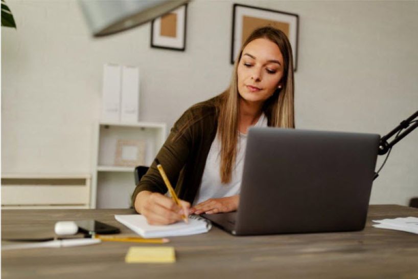 Woman sitting at desk writing on notepad